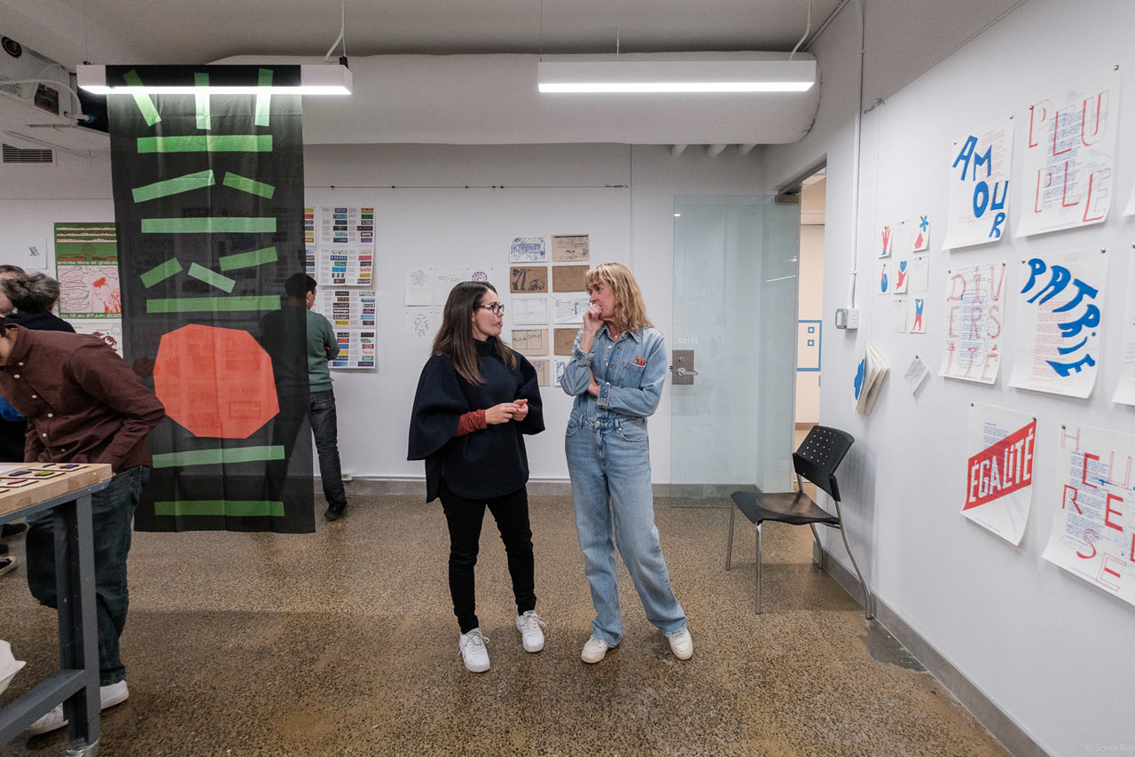 Deux organisatrices discutent lors d'une exposition organisée durant le colloque sur le design social à l'ÉdAC en octobre 2025.