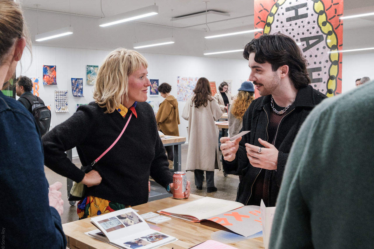 Deux personnes discutent lors d'une exposition organisée durant le colloque sur le design social à l'ÉdAC en octobre 2025.