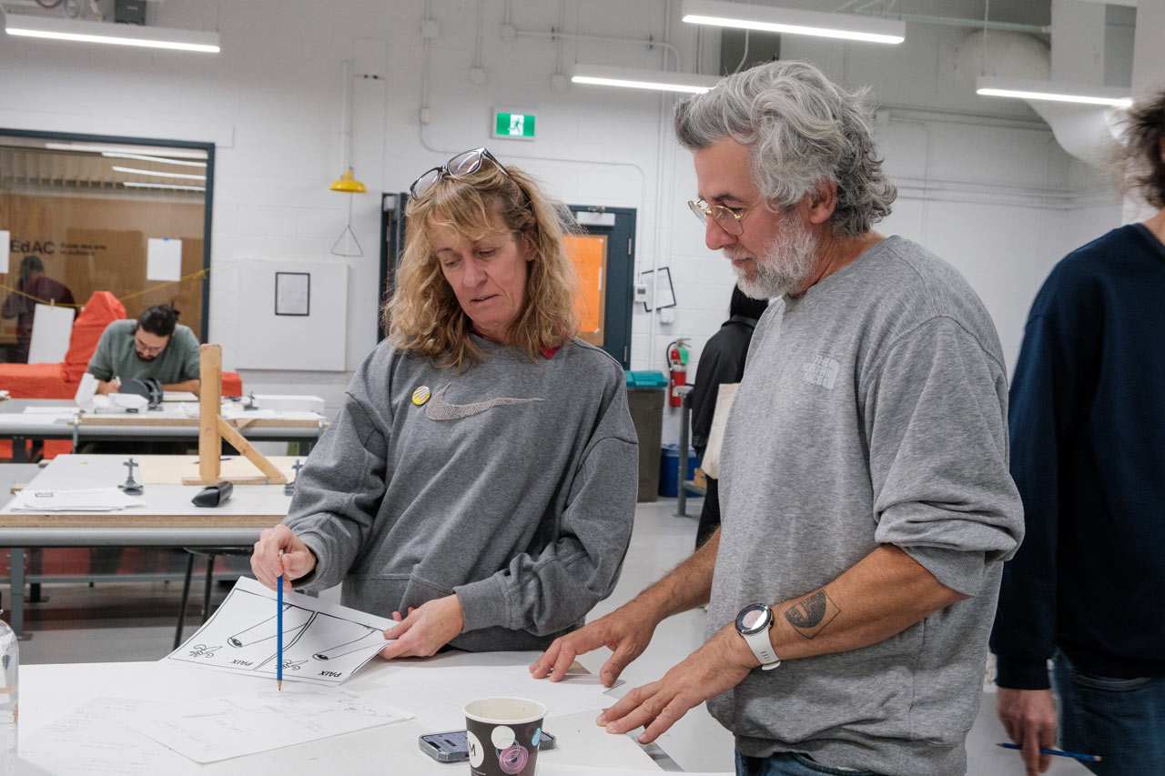 Deux personnes discutent d'une image réalisée durant un atelier de pratique lors du colloque sur le design social organisé à l'ÉdAC en octobre 2025.