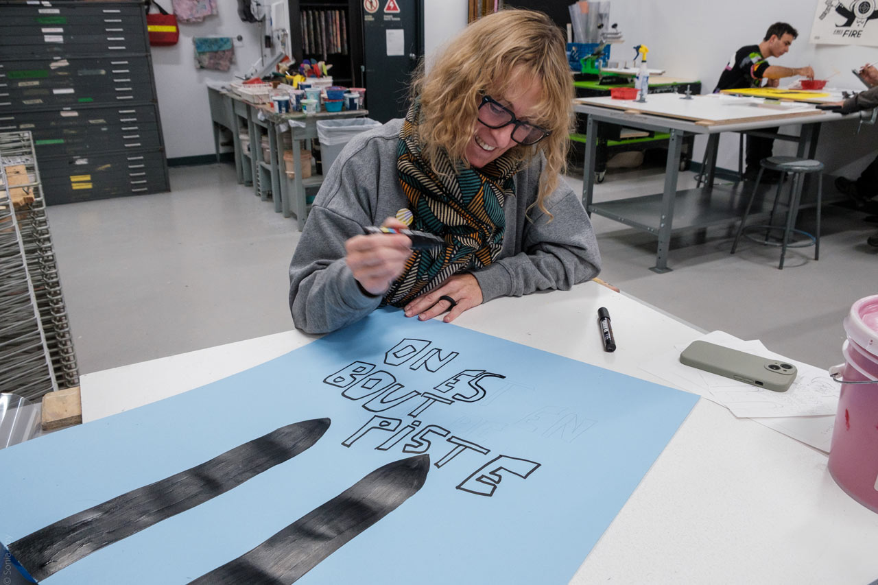 Une personne réalise une affiche dans le cadre d'un atelier de pratique organisé durant le colloque sur le design social à l'ÉdAC en octobre 2025.