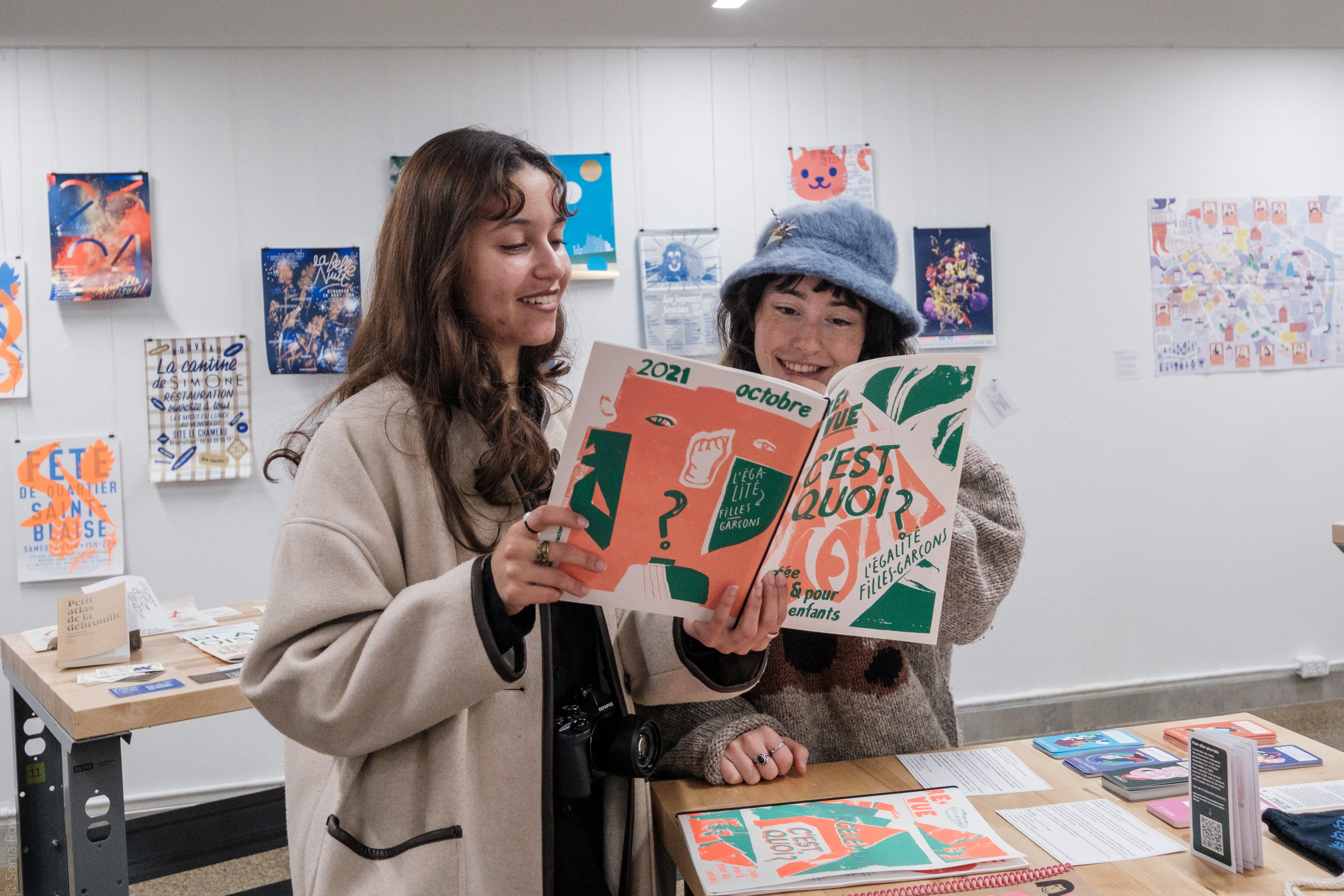 Deux personnes découvrent une publication exposée durant le colloque sur le design social à l'ÉdAC en octobre 2025.