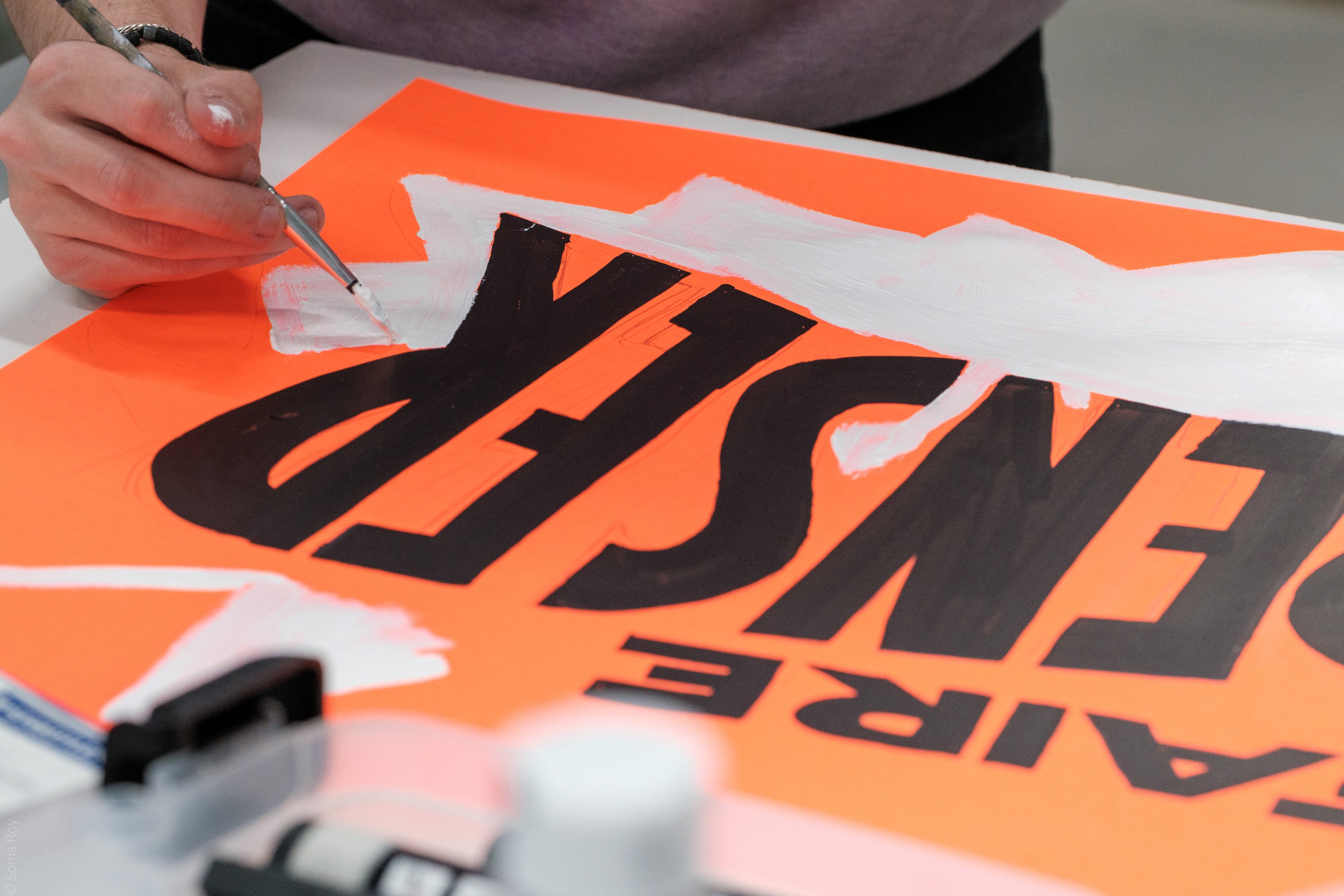 Une personne réalise une affiche dans le cadre d'un atelier de pratique durant le colloque sur le design social organisé à l'ÉdAC en octobre 2025.