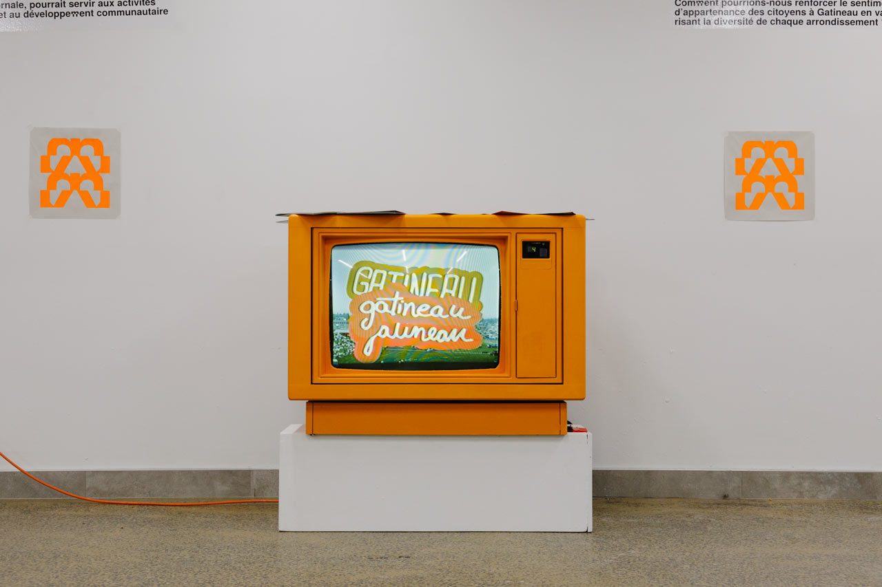 Un vieux poste de télévision peint en orange diffuse des images liées à une exposition de design graphique à l'ÉdAC.