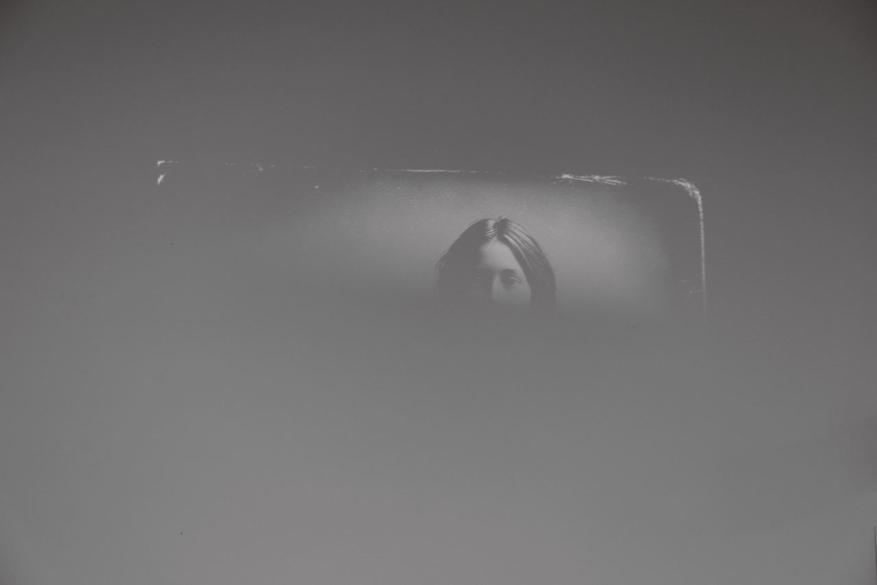 Un fragment de photographie en noir et blanc laisse deviner le visage d'une personne.
