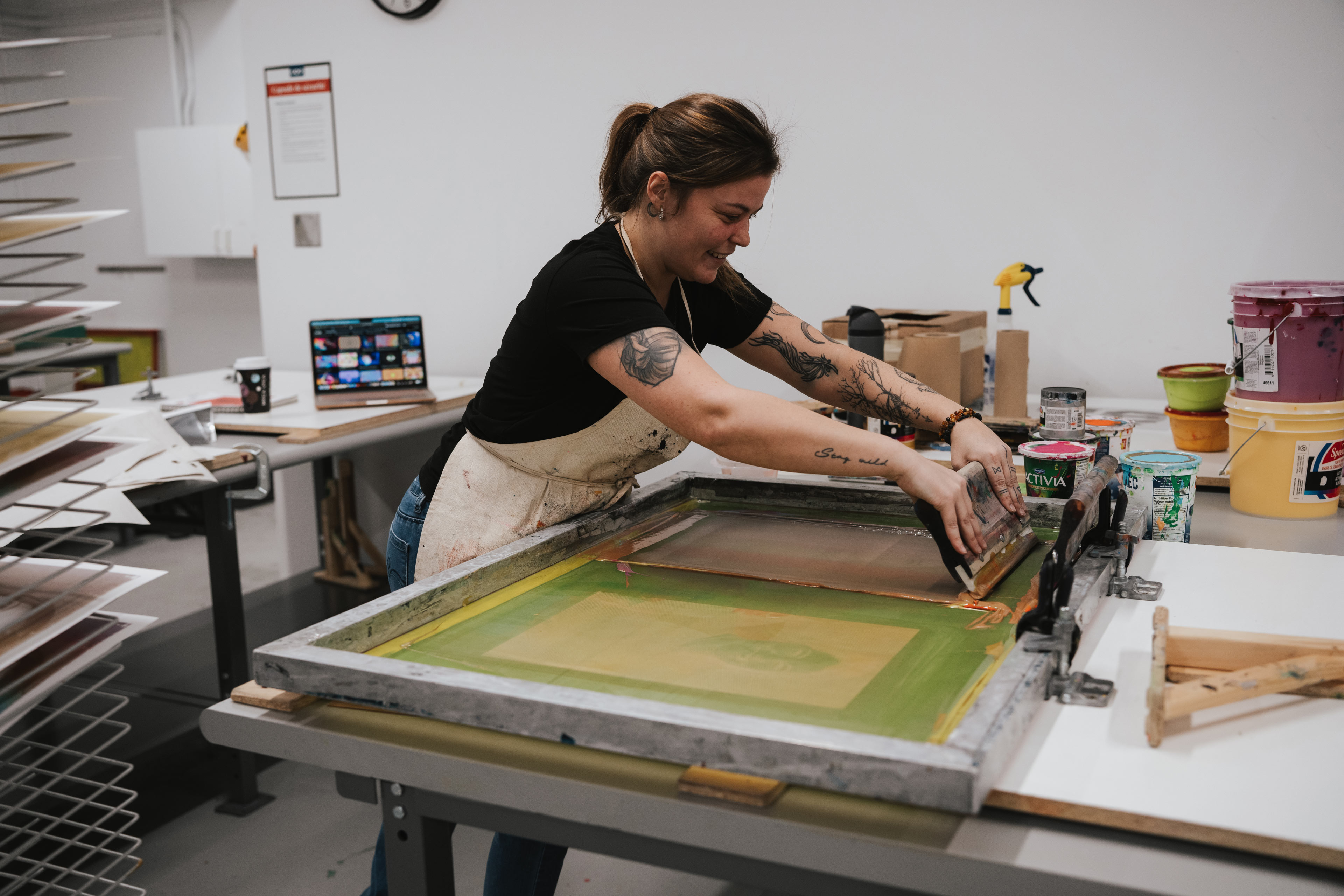 Une personne pratique la sérigraphie dans un atelier de l'ÉdAC.