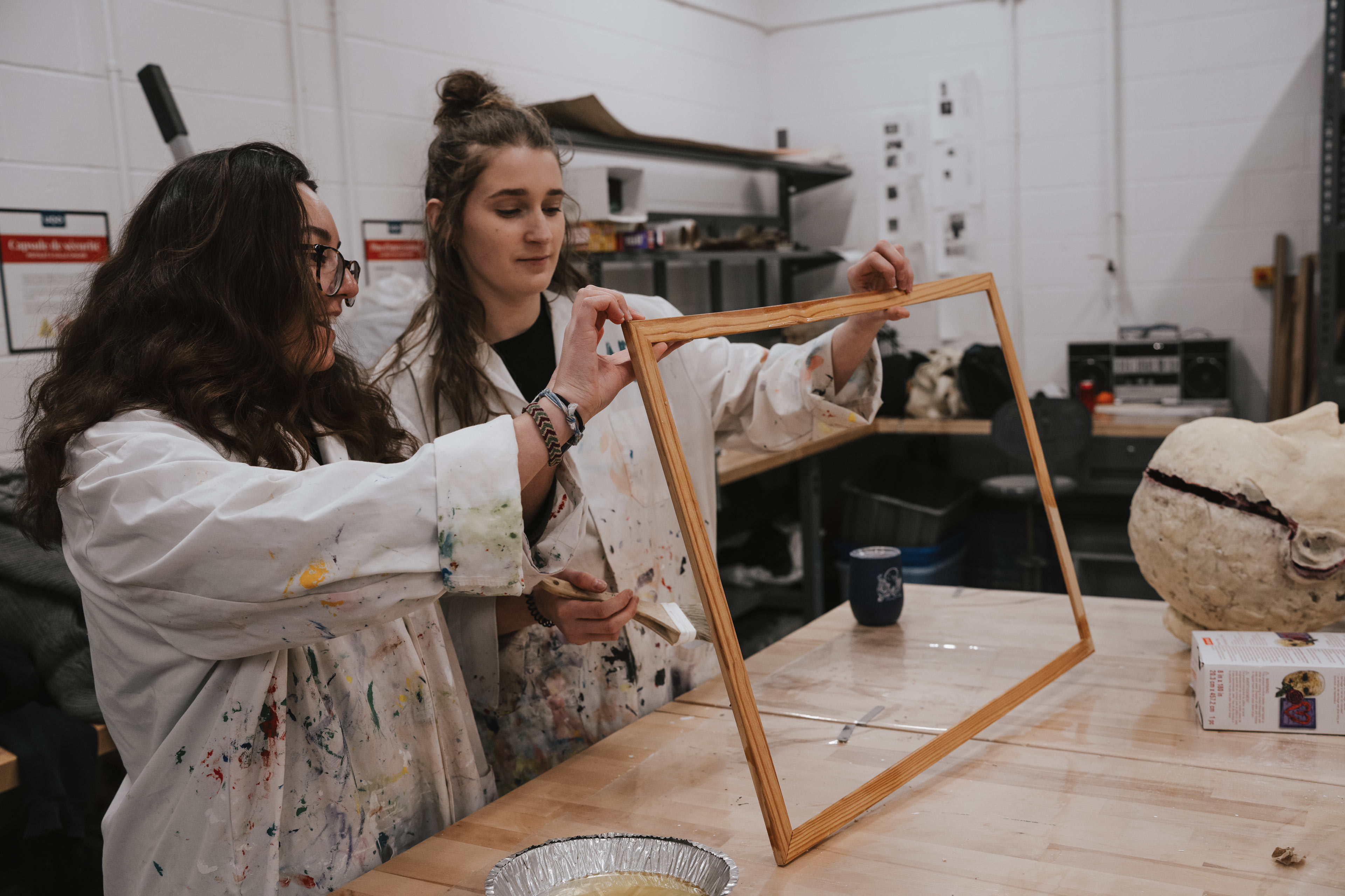 Deux étudiantes préparent un cadre pour un cours de peinture à l'ÉdAC.