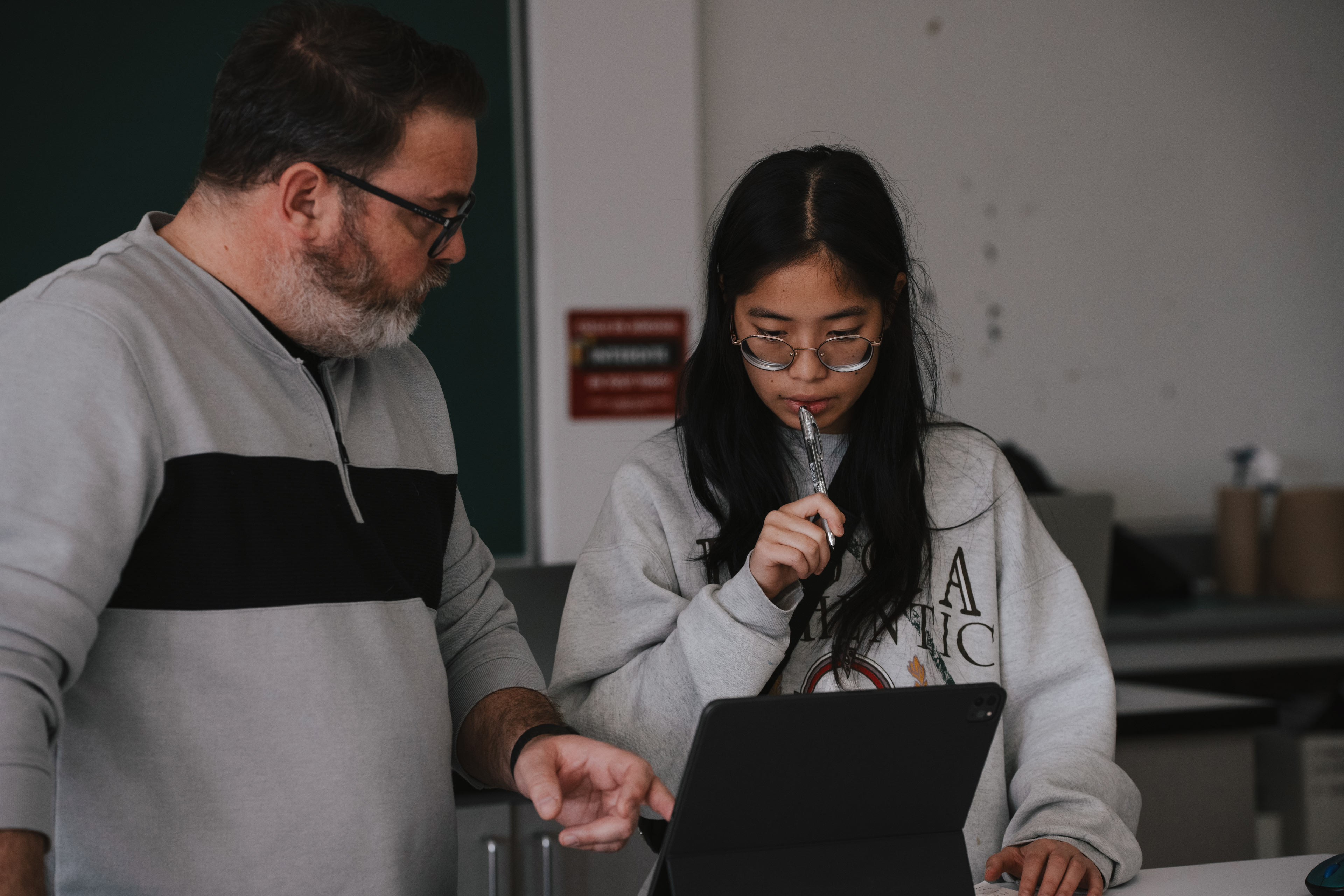 Un enseignant commente le projet d'une étudiante dans un atelier de design graphique à l'ÉdAC.