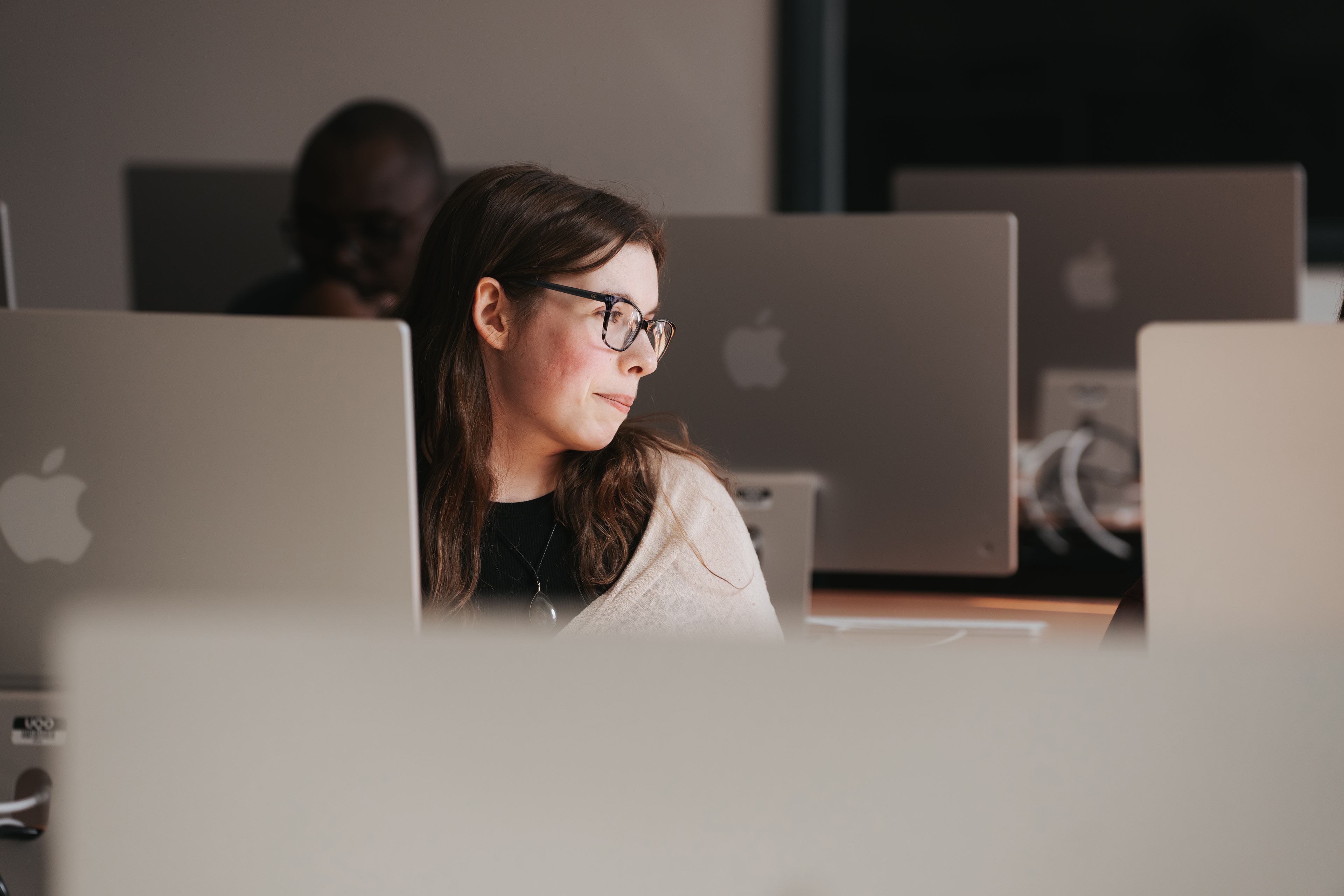 Une personne travaille à l'ordinateur dans un atelier de design graphique à l'ÉdAC.