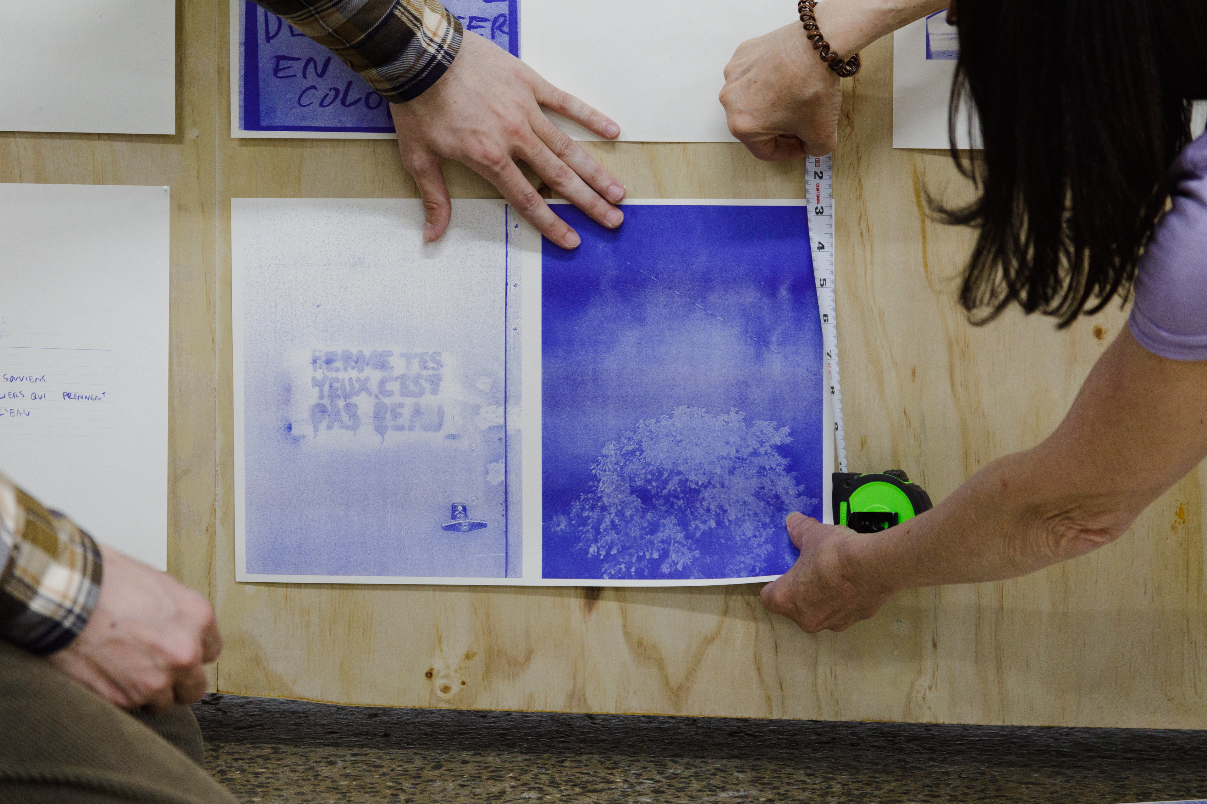 Deux personnes installent des documents imprimés pour une exposition à l'ÉdAC.